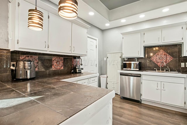 kitchen with white cabinets, dark wood-style floors, stainless steel appliances, and a sink