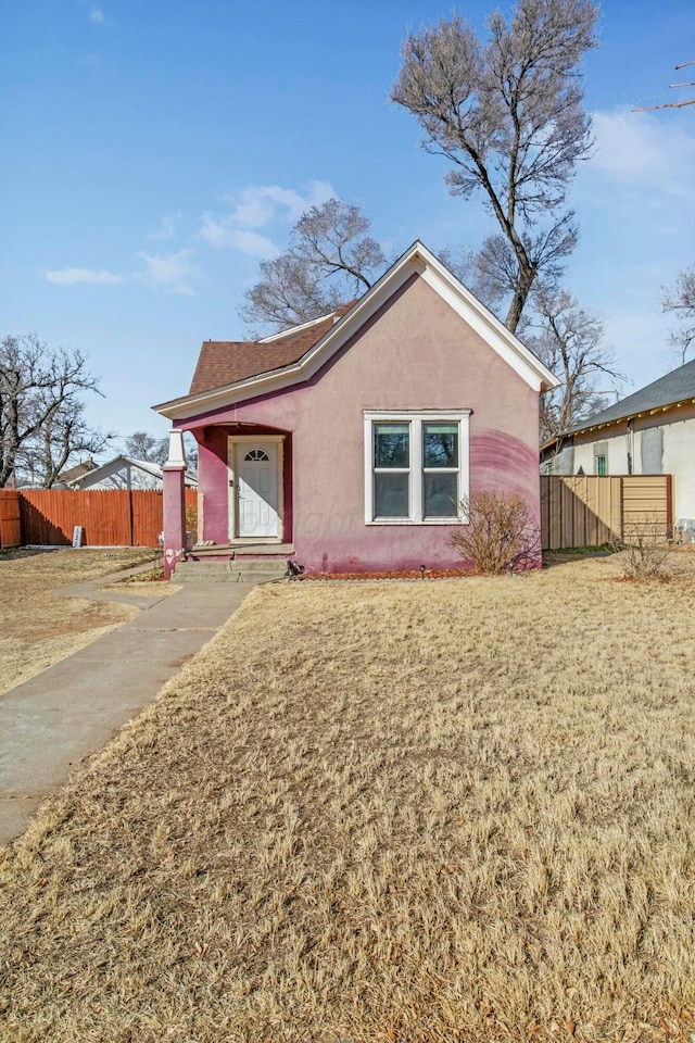 view of front facade featuring a front yard, fence, and stucco siding