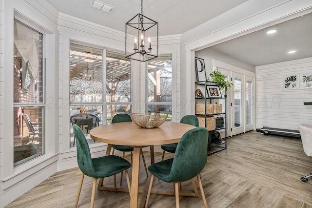 dining room with wooden walls, a chandelier, and light hardwood / wood-style floors