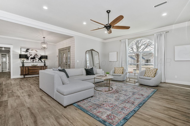 living room with ornamental molding, ceiling fan with notable chandelier, and hardwood / wood-style floors