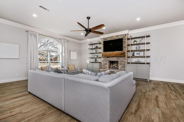 living room featuring a fireplace, crown molding, wood-type flooring, and ceiling fan