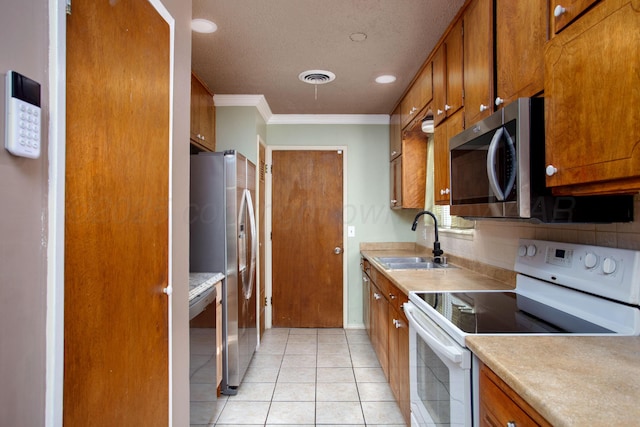 1626 N Apache St, Amarillo, TX 79107 - kitchen with stainless steel appliances, a sink, brown cabinetry, crown molding, and light countertops