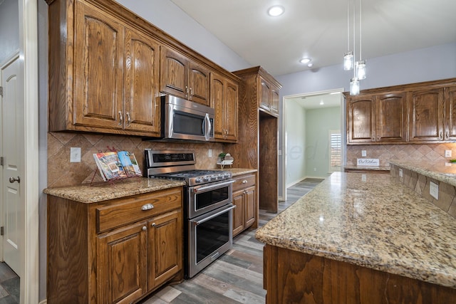 kitchen with light stone counters, wood finished floors, backsplash, and stainless steel appliances
