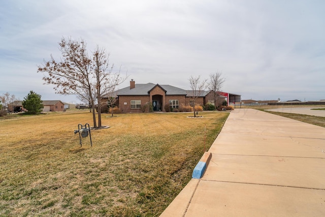 view of front of house featuring a chimney, concrete driveway, and a front lawn