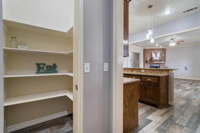 kitchen featuring visible vents, decorative light fixtures, wood finished floors, light stone countertops, and ceiling fan