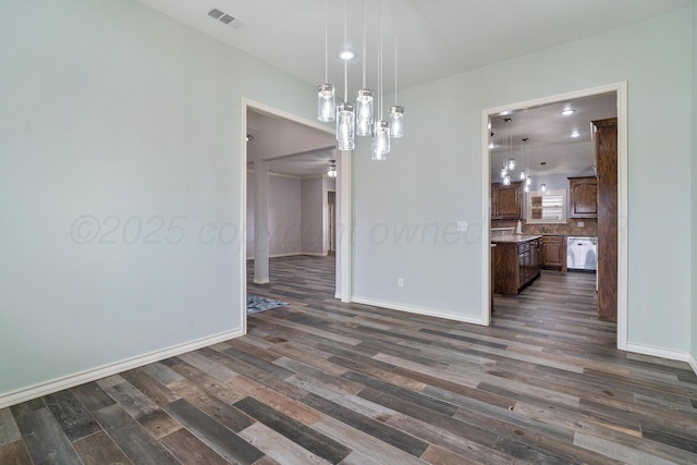 spare room featuring visible vents, baseboards, dark wood-type flooring, and ceiling fan