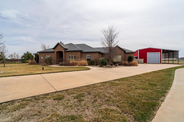 view of front of home featuring an outbuilding, driveway, a detached garage, and a front yard