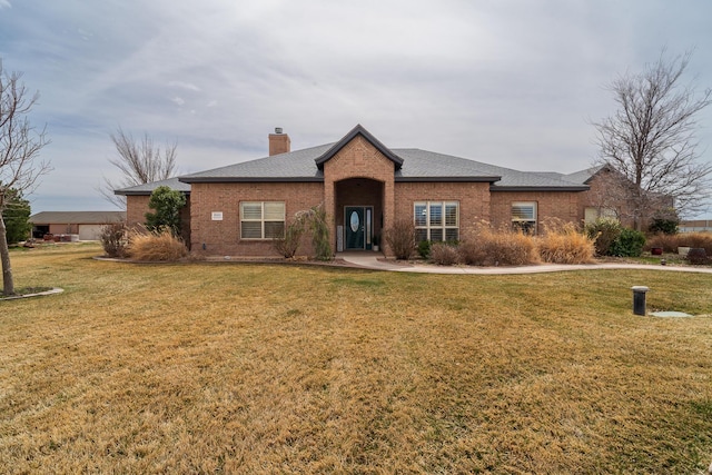 ranch-style home featuring a front lawn, brick siding, roof with shingles, and a chimney