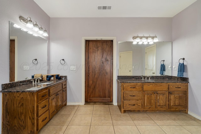 bathroom featuring tile patterned floors, visible vents, baseboards, and two vanities