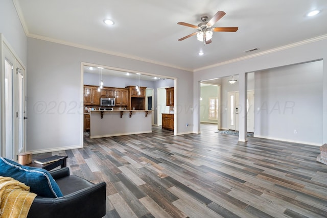 living room with visible vents, a ceiling fan, wood finished floors, crown molding, and baseboards