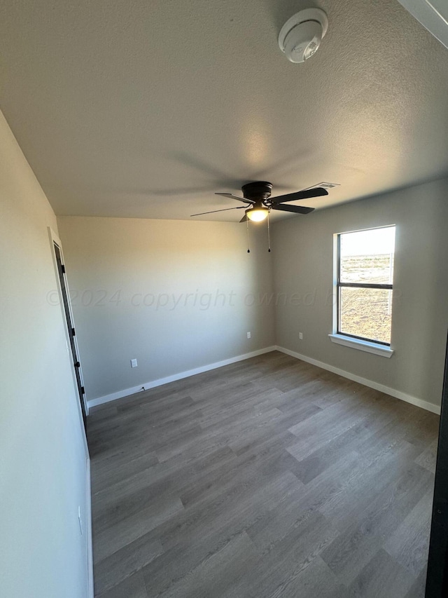 unfurnished room featuring dark wood-type flooring, ceiling fan, and a textured ceiling