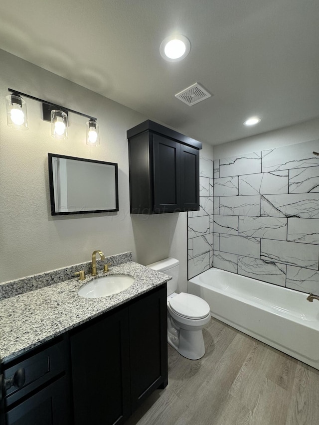 full bathroom with tiled shower / bath, vanity, toilet, and hardwood / wood-style flooring
