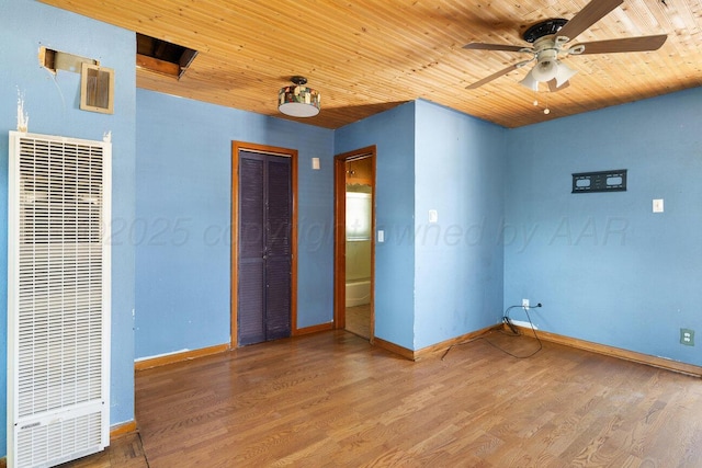 unfurnished bedroom featuring a heating unit, wood ceiling, baseboards, wood finished floors, and a closet