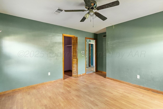 unfurnished bedroom with light wood-style floors, a spacious closet, baseboards, and a ceiling fan