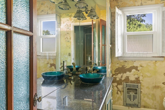 bathroom with radiator heating unit, double vanity, and wallpapered walls