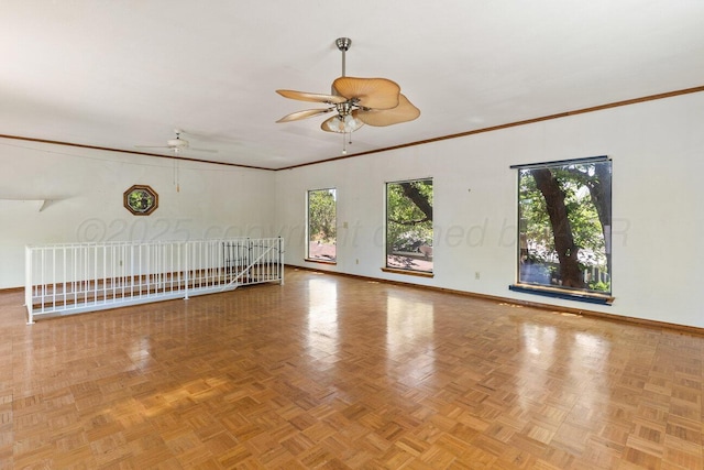 spare room with ceiling fan, baseboards, and crown molding
