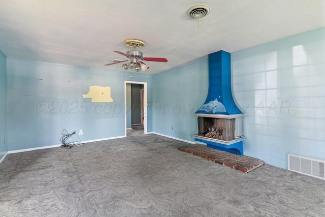 unfurnished living room featuring carpet, baseboards, ceiling fan, and a wood stove