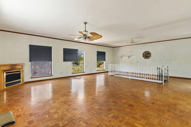 unfurnished living room with ceiling fan, baseboards, crown molding, and a fireplace