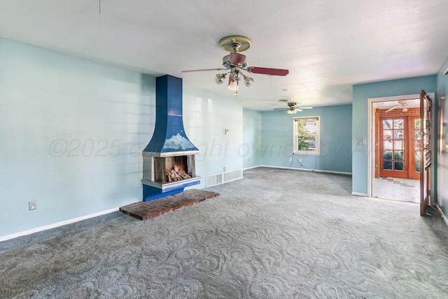 unfurnished living room with carpet flooring, a ceiling fan, and baseboards
