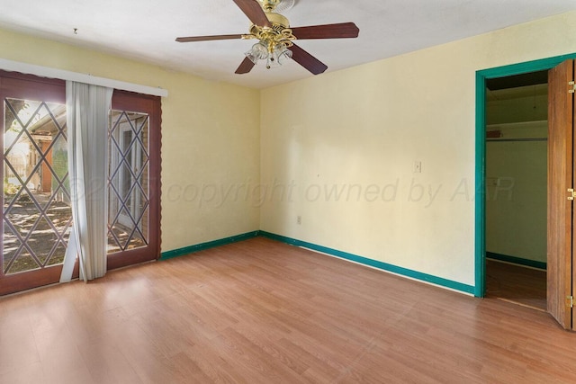 empty room featuring wood finished floors, baseboards, and a ceiling fan