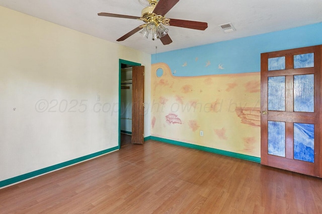 empty room featuring wood finished floors, baseboards, and a ceiling fan