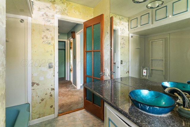 full bathroom with baseboards, vanity, tile patterned flooring, a bath, and wallpapered walls