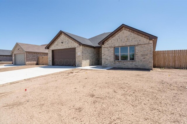 1634 Northridge St, Dumas, TX 79029 - view of front facade with brick siding, fence, an attached garage, and concrete driveway