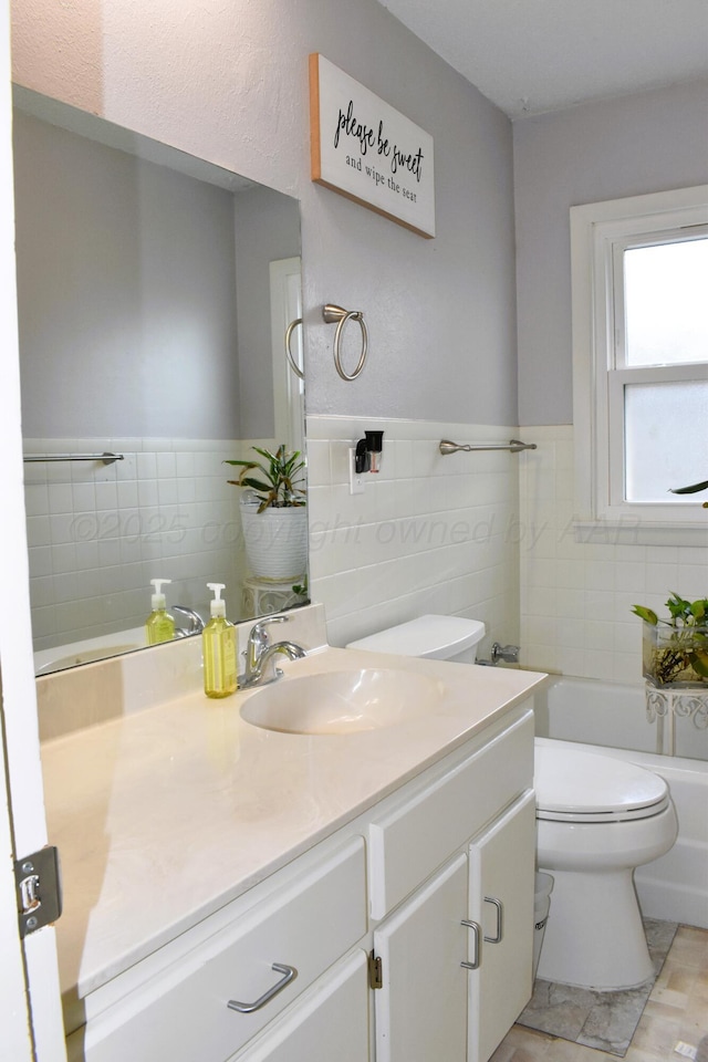 501 Bruce Ave, Dumas, TX 79029 - bathroom with tile walls, vanity, a tub, and a wainscoted wall