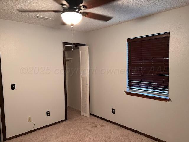 204 SE 15th Ave, Perryton, TX 79070 - unfurnished bedroom with light carpet, a textured ceiling, and a ceiling fan