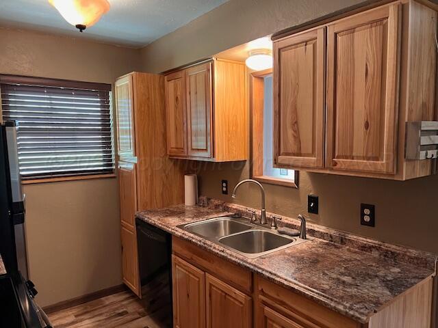 204 SE 15th Ave, Perryton, TX 79070 - kitchen with black dishwasher, light wood-type flooring, and brown cabinets