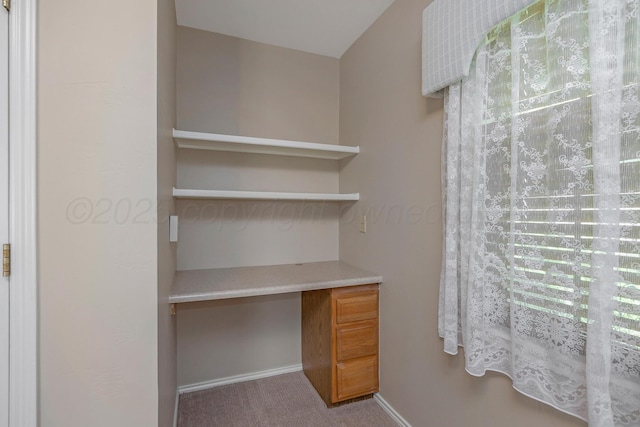 unfurnished office with built in study area, carpet, and baseboards