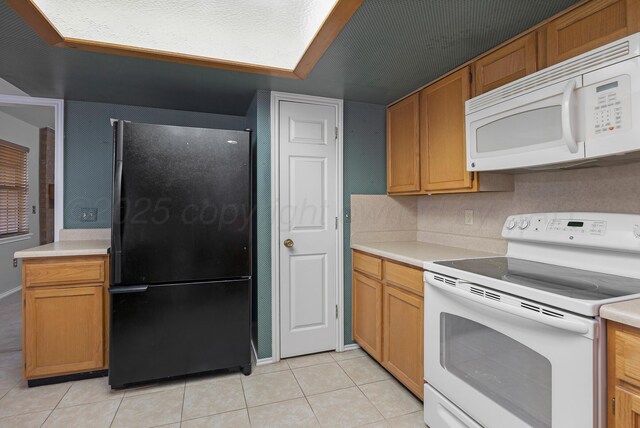kitchen with white appliances, light countertops, light tile patterned flooring, and brown cabinets