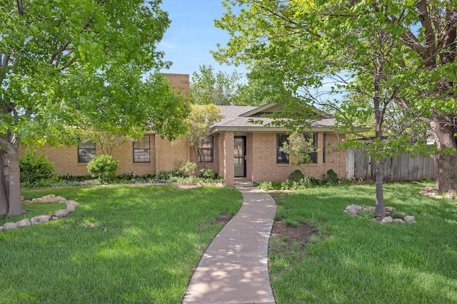view of front of property featuring a front yard, brick siding, a chimney, and roof with shingles