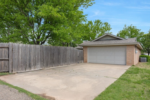 garage with central air condition unit, fence, and concrete driveway