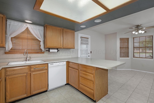 kitchen with dishwasher, a sink, a peninsula, light tile patterned floors, and light countertops