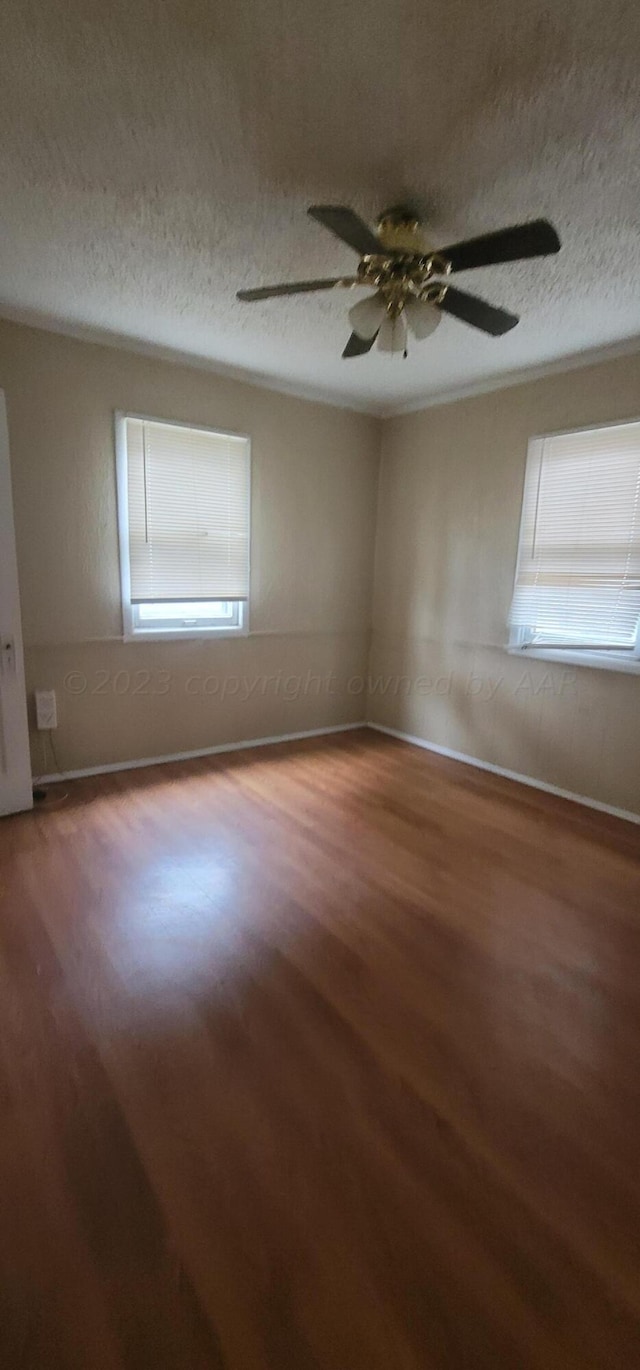 empty room featuring a healthy amount of sunlight, hardwood / wood-style floors, and a textured ceiling