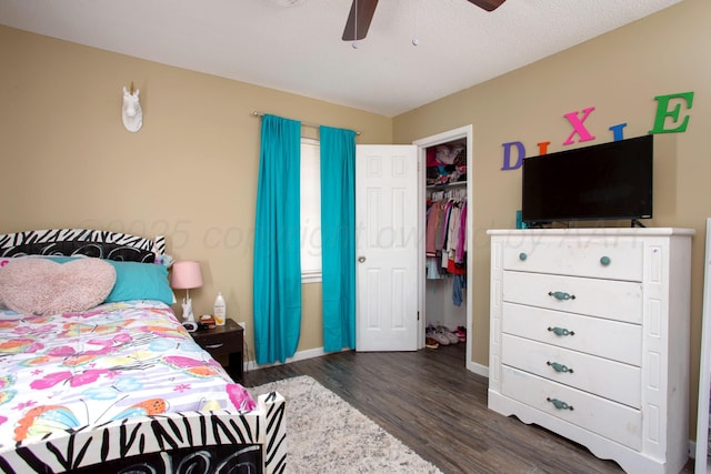 bedroom featuring wood finished floors, baseboards, a closet, a ceiling fan, and a walk in closet