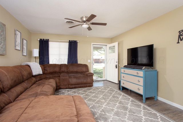 living area featuring wood finished floors, a ceiling fan, and baseboards