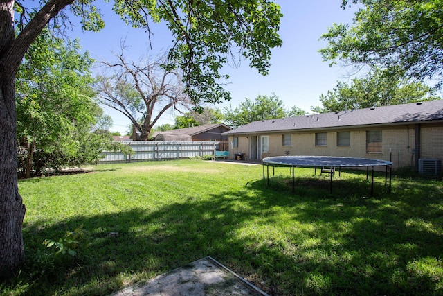 view of yard with a trampoline and central AC unit