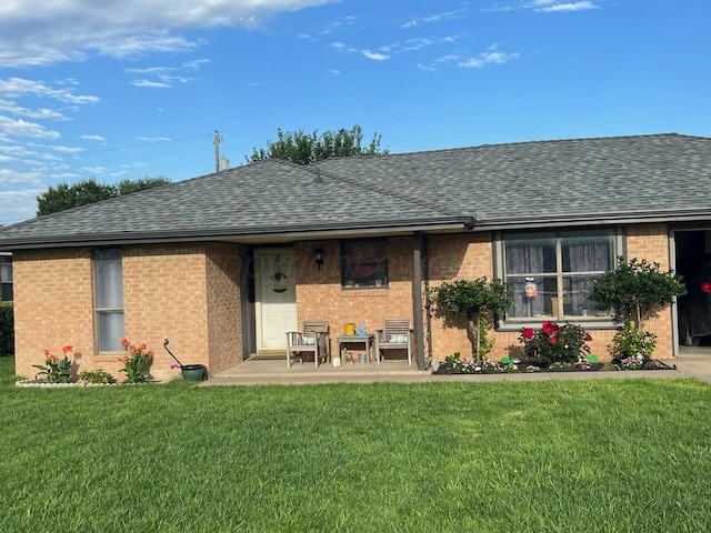 back of house with brick siding, a yard, and roof with shingles