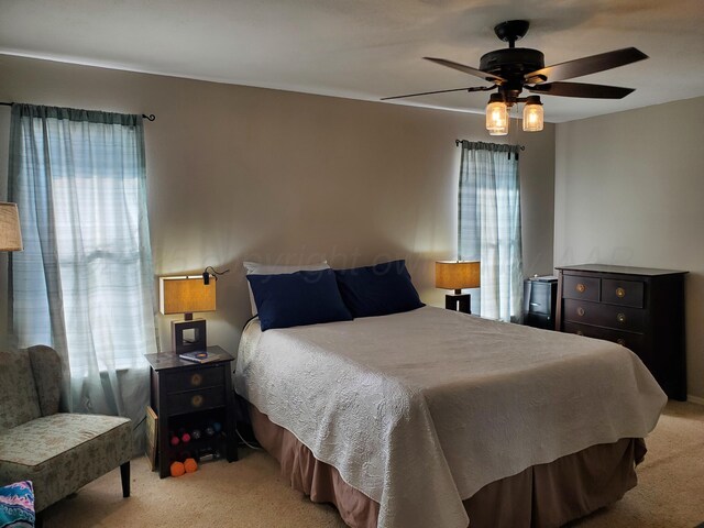 bedroom with light carpet, multiple windows, and ceiling fan