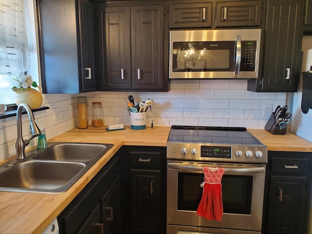 kitchen with a sink, decorative backsplash, wood counters, and stainless steel appliances