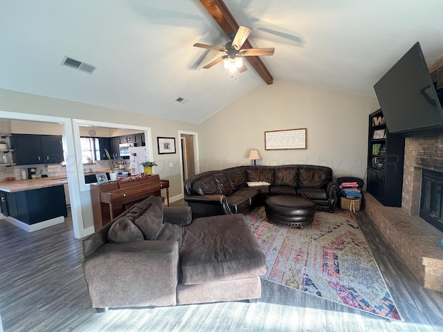 living area featuring wood finished floors, lofted ceiling with beams, a fireplace, and visible vents