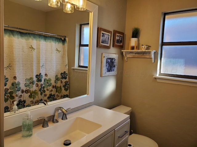 full bath with toilet, an inviting chandelier, and vanity