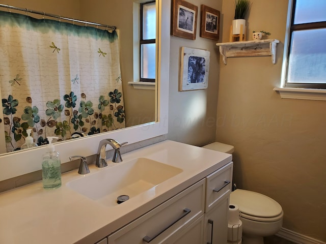 bathroom with a healthy amount of sunlight, toilet, and vanity