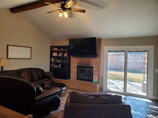 living area with lofted ceiling with beams, ceiling fan, and a fireplace