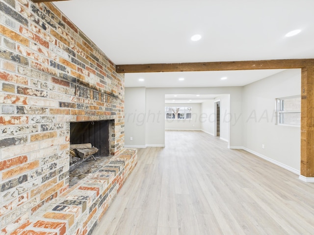 unfurnished living room featuring light wood finished floors, plenty of natural light, baseboards, and beamed ceiling