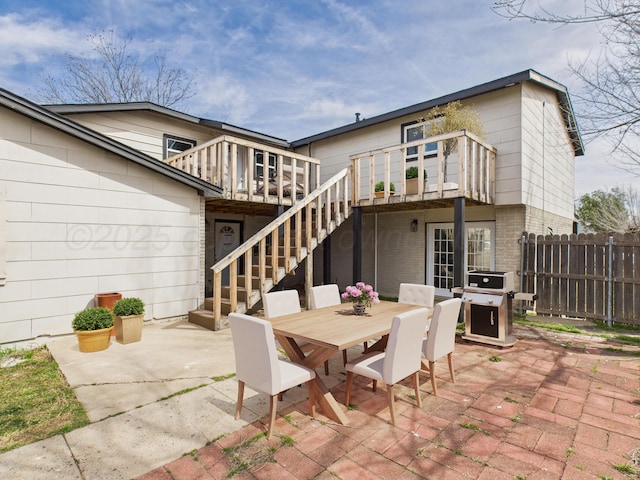 view of patio with stairway, area for grilling, a deck, fence, and outdoor dining area