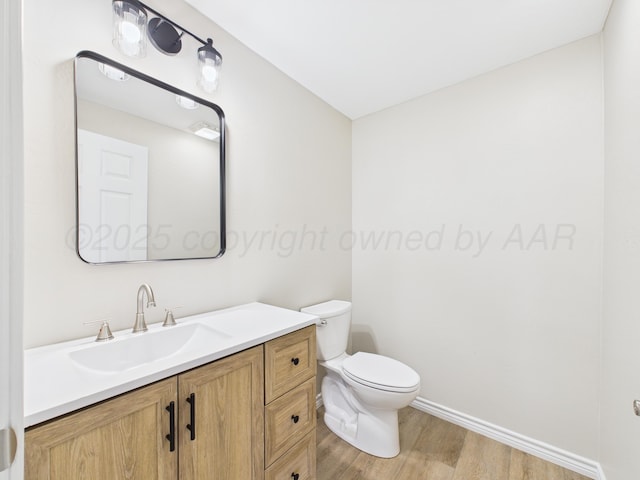 bathroom featuring wood finished floors, toilet, and vanity
