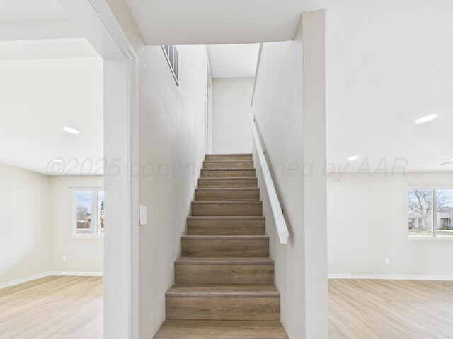 staircase featuring baseboards and wood finished floors